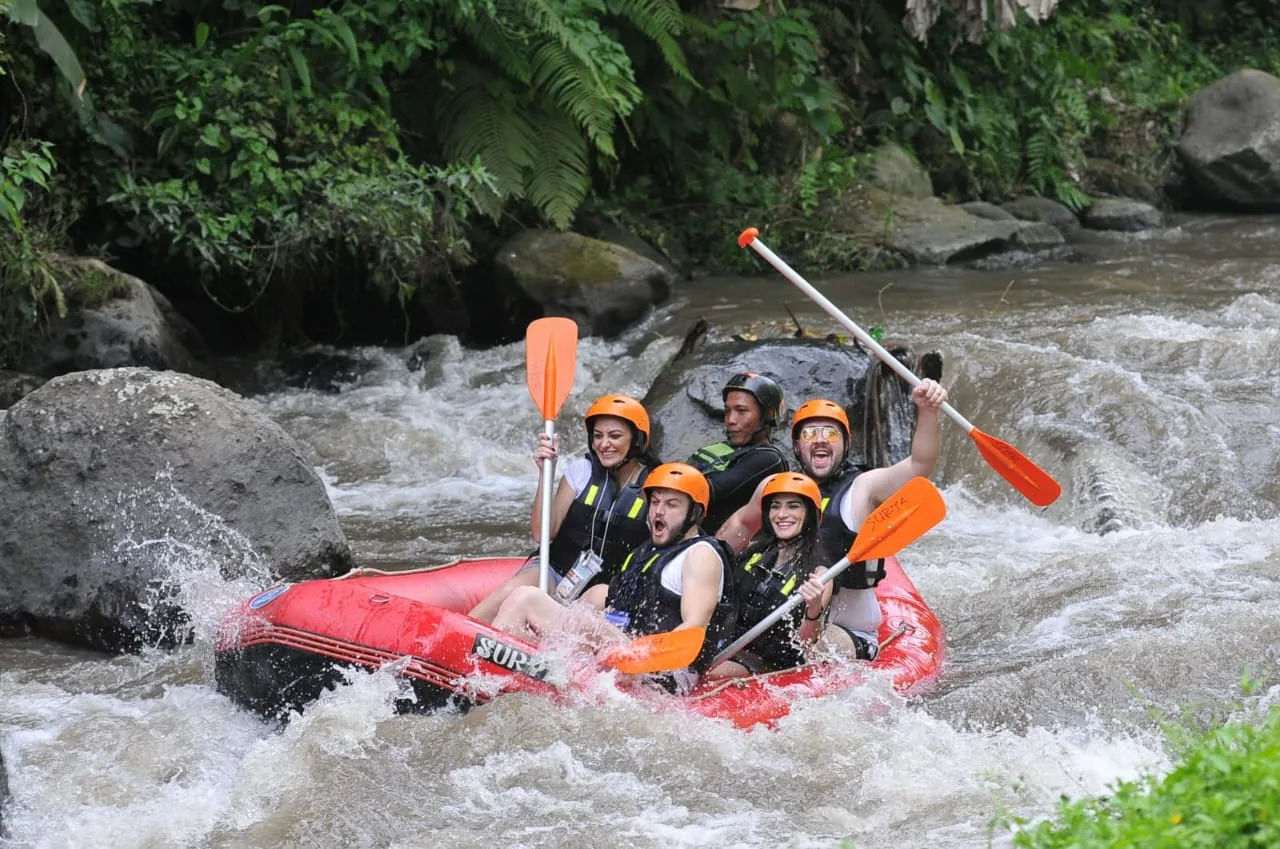 Guests paddling a red raft through river rapids in Bali.